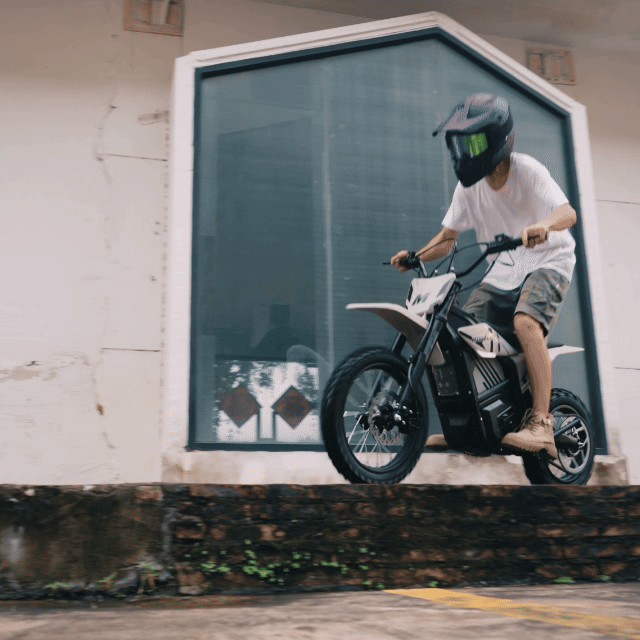 Rider jumping a Mudliz electric dirt bike from a loading platform