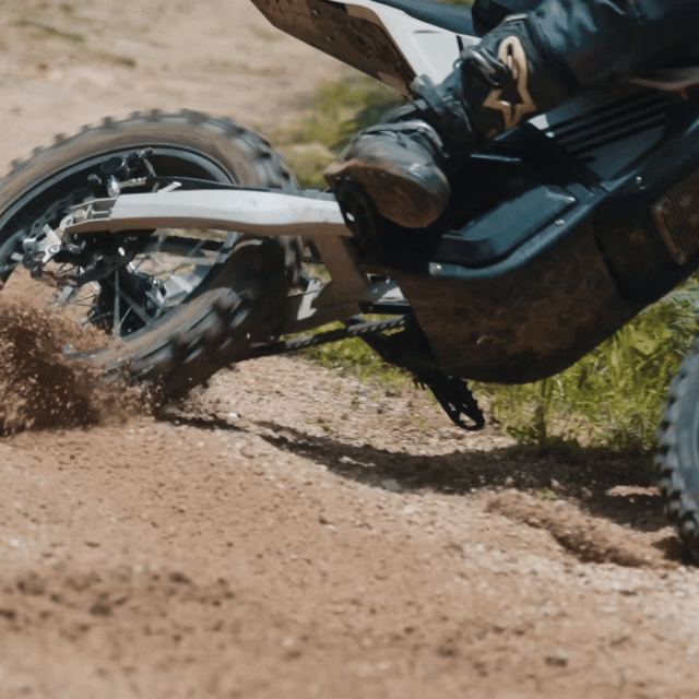 Mudliz electric dirt bike rear wheel throwing dirt on a trail