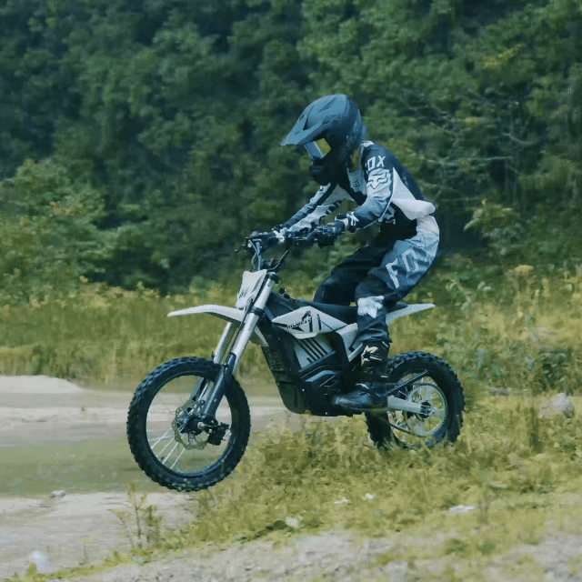 Rider on a Mudliz electric dirt bike on a forest trail
